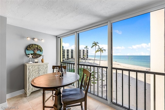 sunroom / solarium featuring a water view and a beach view