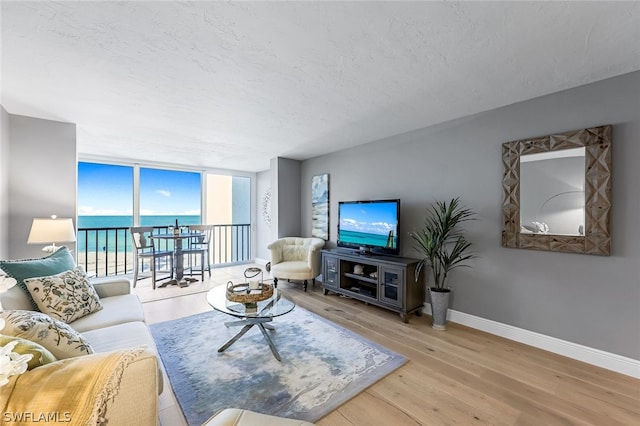 living room with a water view, a textured ceiling, and light wood-type flooring