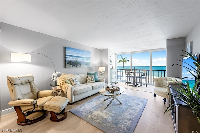 living room featuring a water view, expansive windows, and hardwood / wood-style flooring