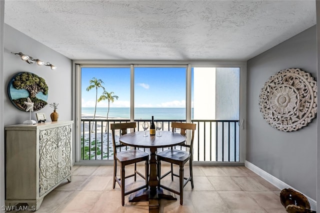 dining room featuring light tile flooring, a water view, and a textured ceiling