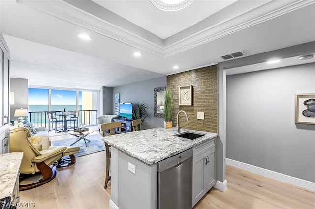 kitchen featuring a kitchen bar, light hardwood / wood-style flooring, dishwasher, light stone counters, and sink