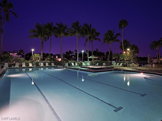 pool at night featuring a patio area