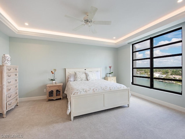 bedroom with light carpet, a tray ceiling, and ceiling fan