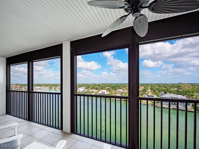 unfurnished sunroom featuring ceiling fan and a water view