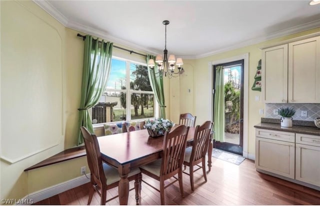 dining area with crown molding, light hardwood / wood-style floors, and an inviting chandelier