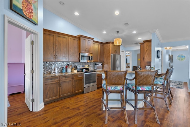 kitchen featuring dark hardwood / wood-style flooring, stainless steel appliances, crown molding, pendant lighting, and a breakfast bar area