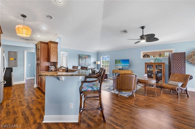 kitchen featuring kitchen peninsula, ceiling fan, crown molding, dark wood-type flooring, and stone counters