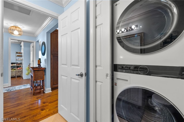 clothes washing area with wood-type flooring, stacked washer / dryer, and ornamental molding