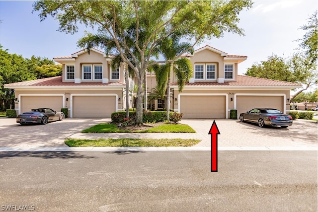 view of property featuring driveway, stucco siding, and a tiled roof