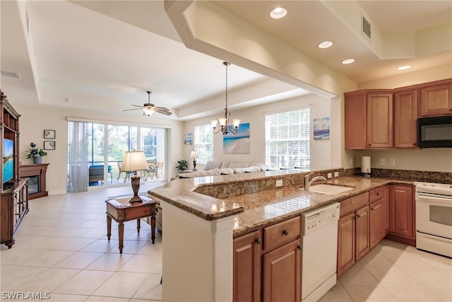 kitchen featuring white appliances, a raised ceiling, a sink, and open floor plan