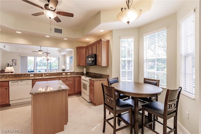 kitchen featuring white appliances, plenty of natural light, a center island, pendant lighting, and a sink