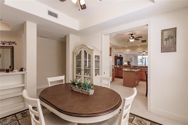 dining space featuring a ceiling fan, a tray ceiling, visible vents, and baseboards