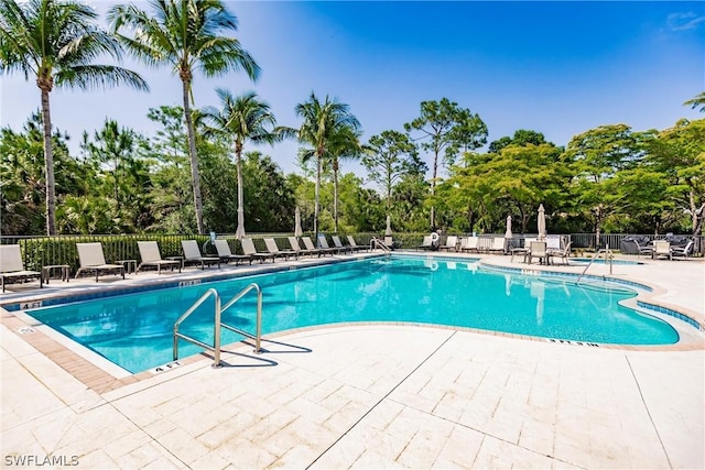 pool with a patio area and fence