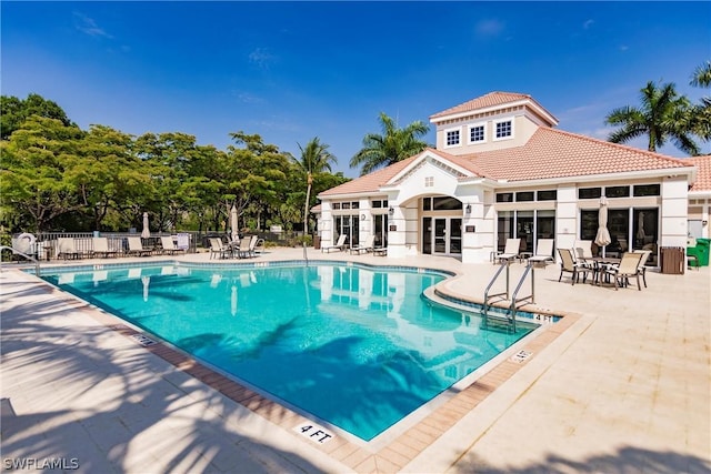 community pool with a patio and fence