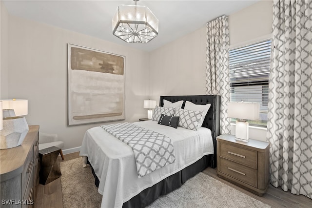 bedroom with light hardwood / wood-style floors and an inviting chandelier