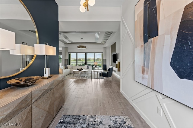 hallway featuring hardwood / wood-style flooring, a raised ceiling, and crown molding