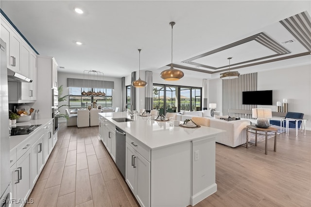 kitchen featuring stainless steel appliances, a center island with sink, white cabinets, sink, and light wood-type flooring