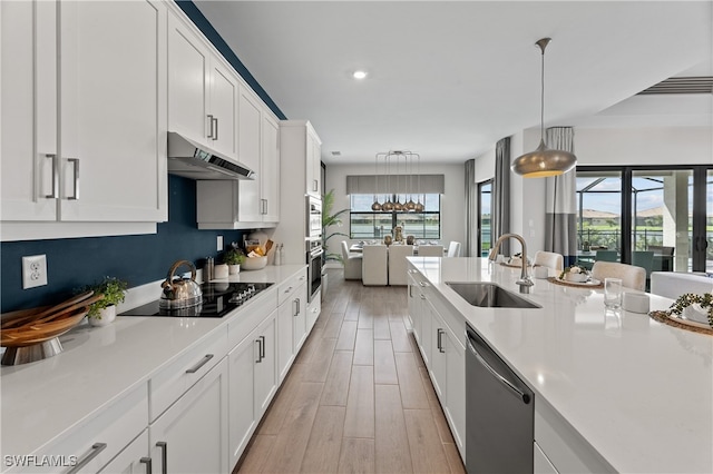 kitchen with pendant lighting, light countertops, a sink, dishwasher, and under cabinet range hood