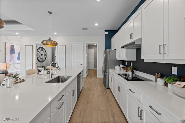 kitchen featuring black electric cooktop, decorative light fixtures, white cabinets, light wood-type flooring, and sink