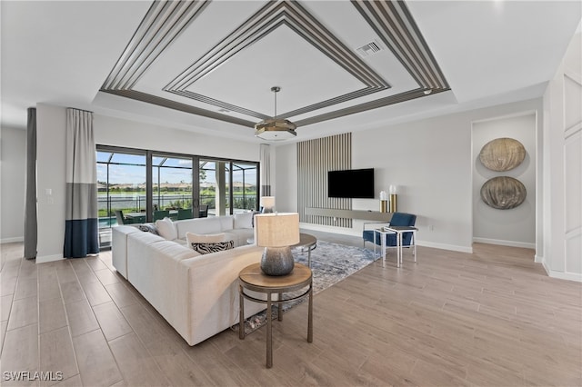 living room featuring light hardwood / wood-style flooring and a tray ceiling