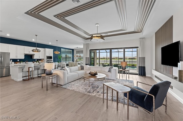 living room featuring light hardwood / wood-style flooring and a raised ceiling