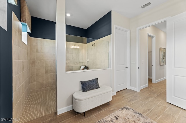 bathroom with tiled shower and tile patterned flooring