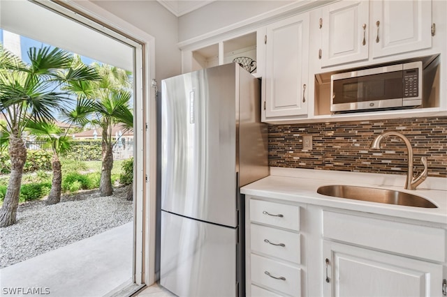 kitchen featuring white cabinets, stainless steel appliances, tasteful backsplash, and sink