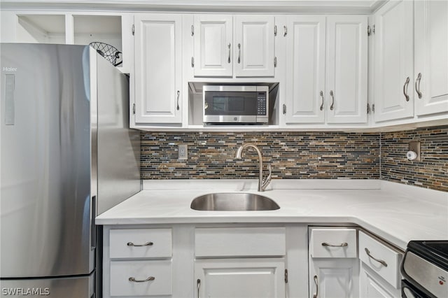 kitchen with decorative backsplash, stainless steel appliances, white cabinetry, and sink