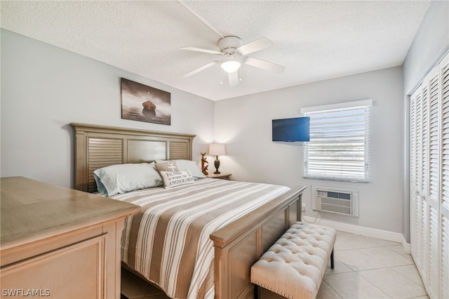 tiled bedroom with a wall mounted air conditioner, a textured ceiling, a closet, and ceiling fan