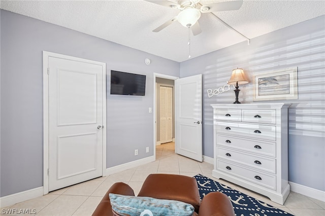 sitting room with ceiling fan, light tile patterned flooring, and a textured ceiling