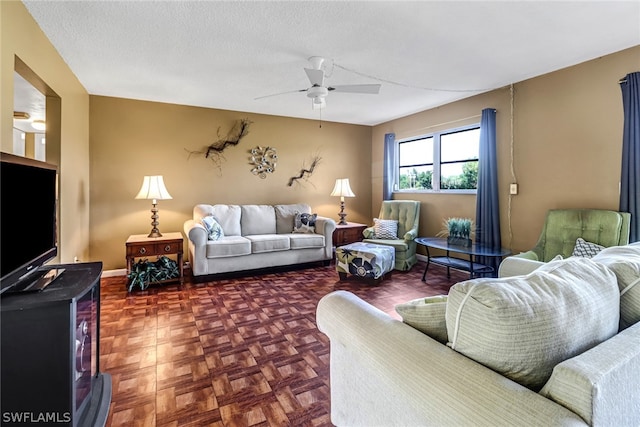 living room featuring ceiling fan, parquet floors, and a textured ceiling