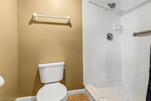 bathroom featuring tiled shower, parquet floors, and toilet