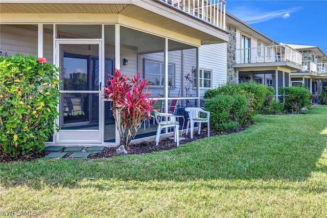 view of side of home with a yard, a sunroom, and a balcony