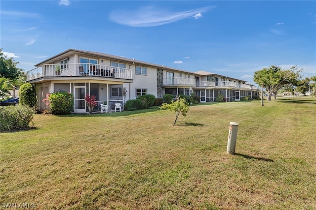 rear view of property with a balcony and a yard