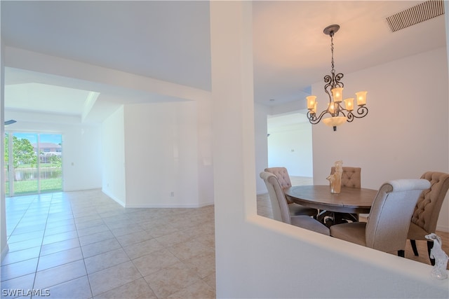 tiled dining area featuring a raised ceiling and a notable chandelier