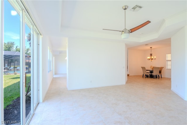 spare room featuring ceiling fan with notable chandelier, a wealth of natural light, and a tray ceiling