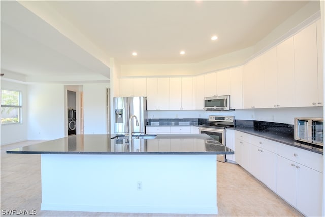 kitchen with white cabinets, a center island with sink, appliances with stainless steel finishes, and light tile flooring