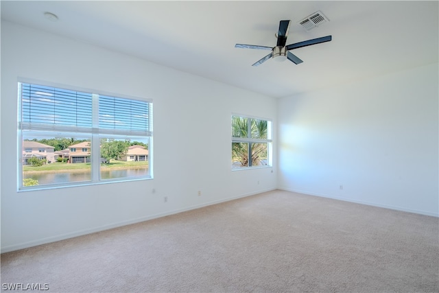 carpeted empty room featuring ceiling fan and a water view