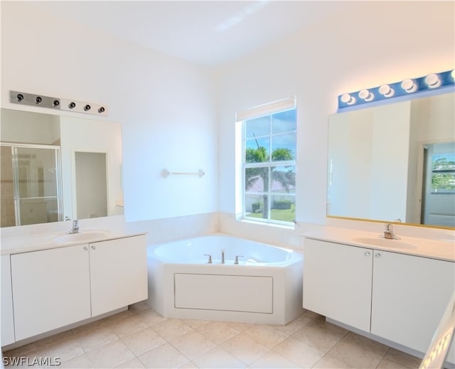 bathroom with a healthy amount of sunlight, double vanity, tile floors, and separate shower and tub