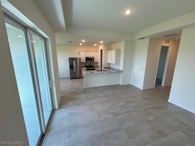 kitchen featuring kitchen peninsula, appliances with stainless steel finishes, a healthy amount of sunlight, sink, and white cabinetry