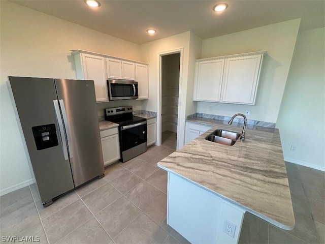 kitchen featuring light stone countertops, appliances with stainless steel finishes, sink, light tile patterned floors, and white cabinetry