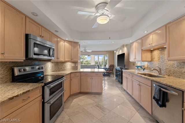 kitchen featuring kitchen peninsula, light brown cabinetry, stainless steel appliances, and sink