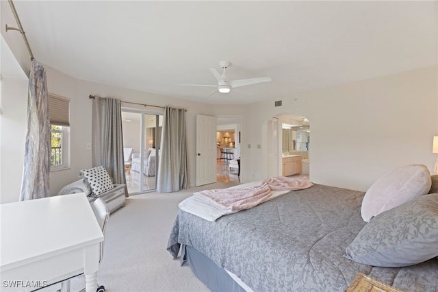 bedroom featuring light colored carpet, ceiling fan, and ensuite bathroom