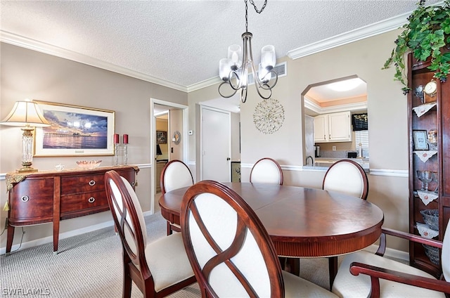 dining area with a chandelier, crown molding, light colored carpet, and a textured ceiling