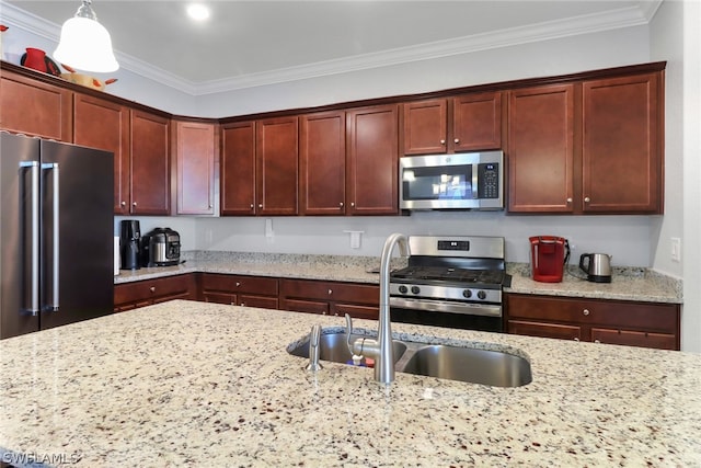 kitchen with appliances with stainless steel finishes, ornamental molding, light stone counters, and pendant lighting