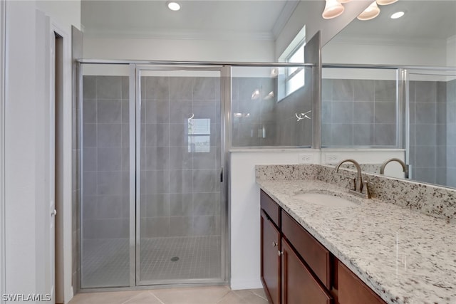 bathroom with a shower with door, crown molding, vanity, and tile patterned floors