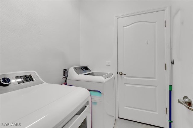 laundry area featuring washer and clothes dryer and tile patterned flooring