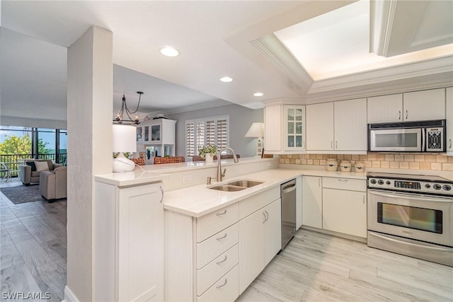 kitchen with white cabinets, kitchen peninsula, sink, and appliances with stainless steel finishes