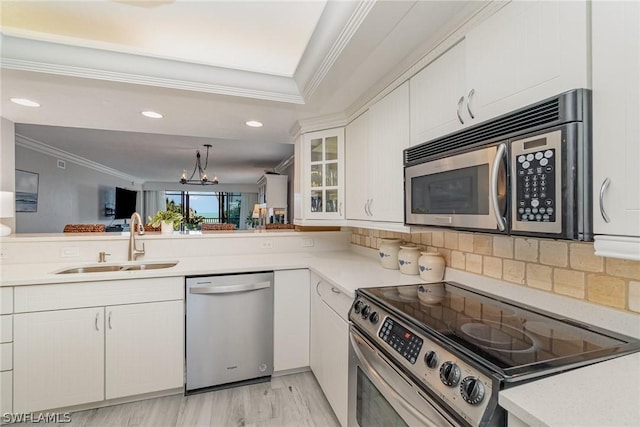 kitchen with white cabinets, sink, ornamental molding, a notable chandelier, and stainless steel appliances