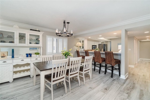 dining area featuring a notable chandelier, light hardwood / wood-style floors, and crown molding